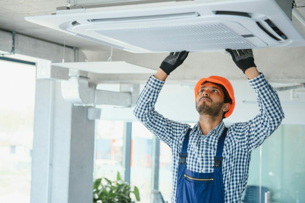 Technicien contrôlant le filtre d’une climatisation cassette au plafond